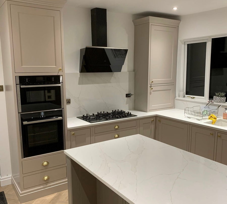 The cooker wall: induction hob, black chimney extractor and a stone splashback