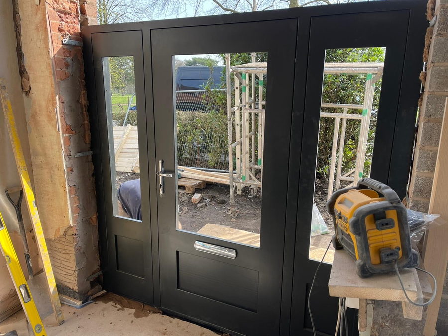 The entrance door set glazed and propped, part-way through the fit