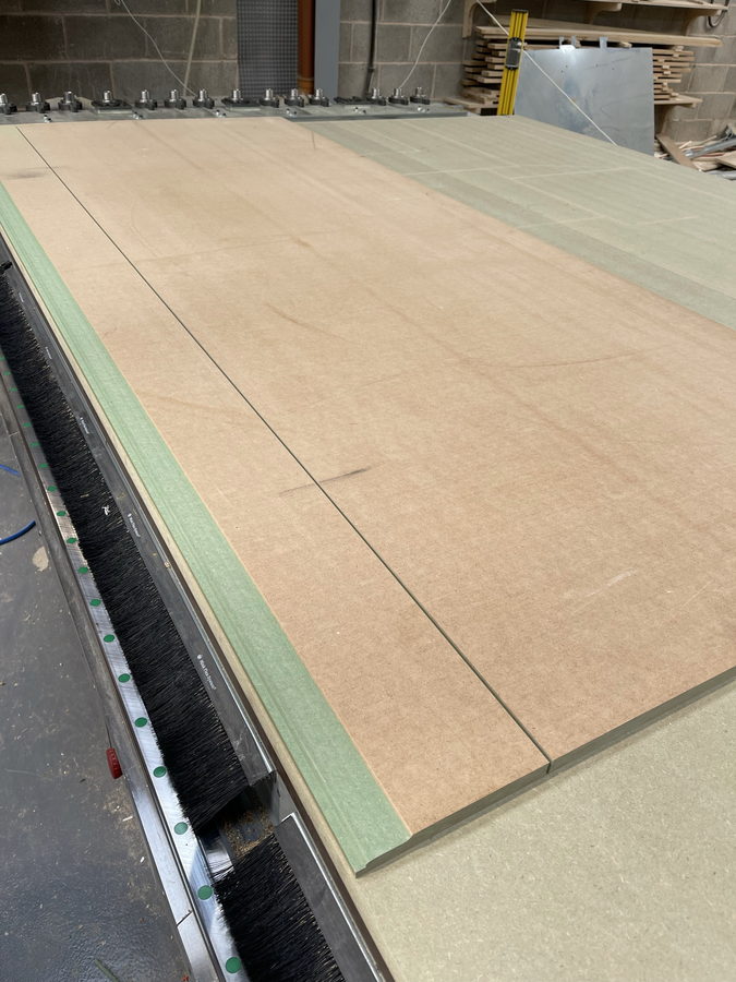 A full jumbo board on the vacuum bed, mid-cut