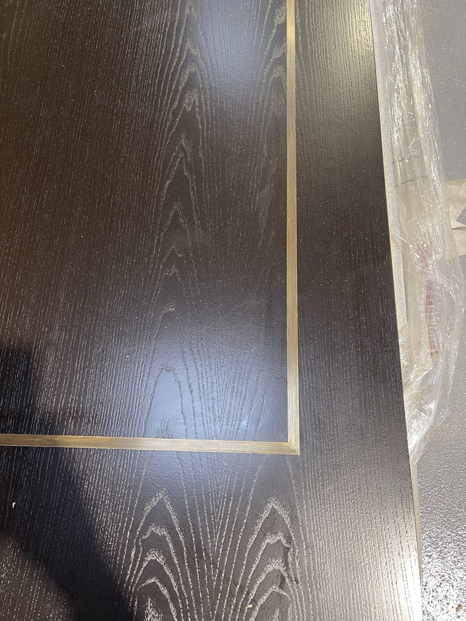 The inlay close to: a single fine brass line in dark stained oak