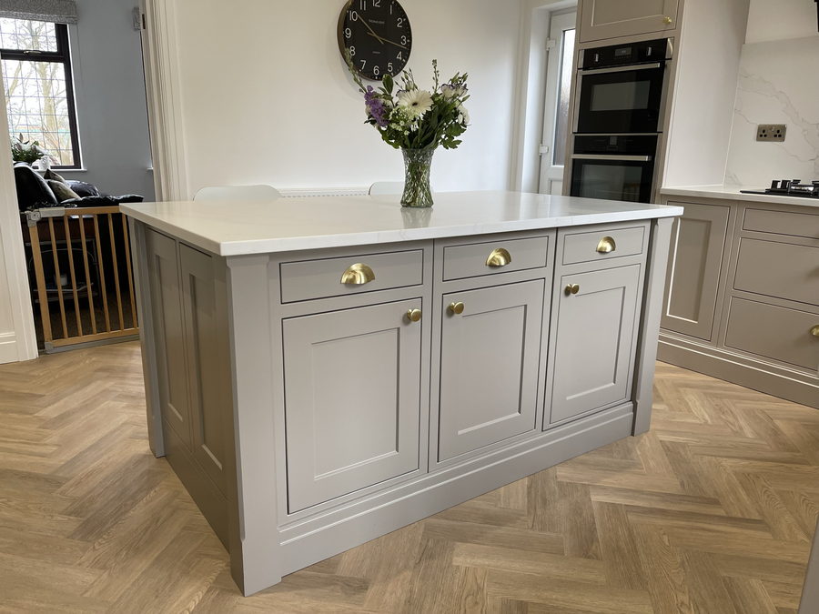 Taupe shaker island with a white quartz top, brass cup handles and panelled ends