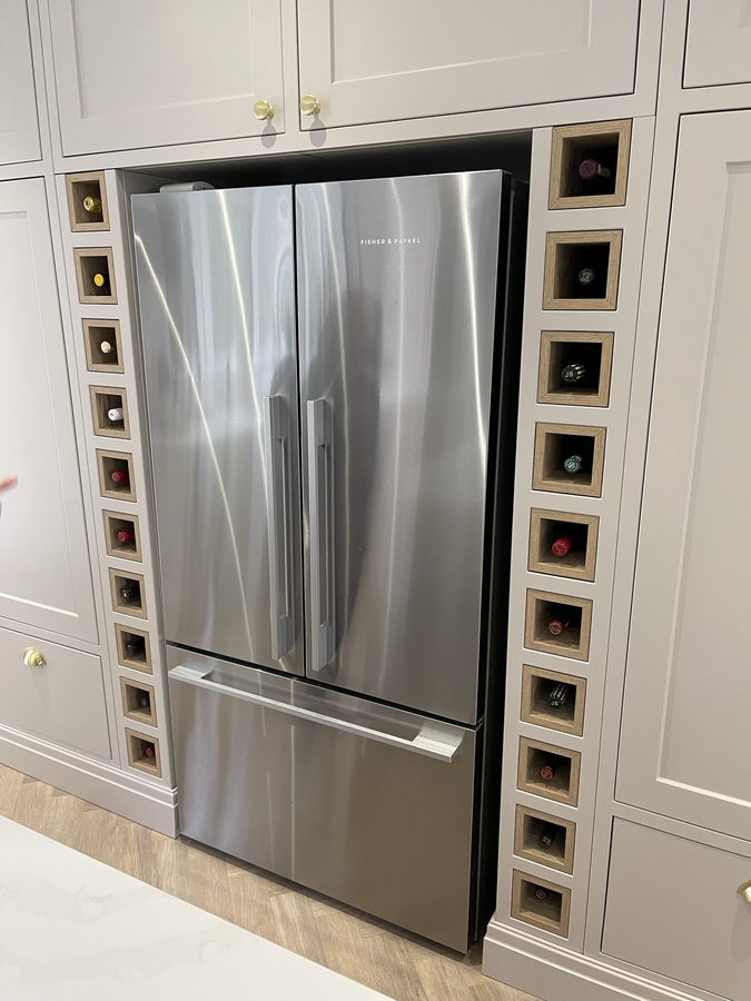 An American fridge framed by filled wine-bottle cubbies