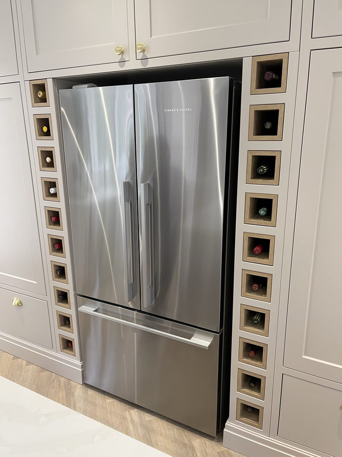 Wine cubby columns on both sides of the fridge, built into the tall run