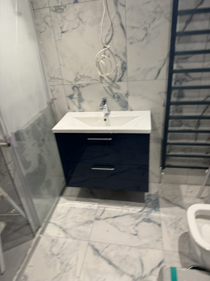 A navy gloss wall-hung vanity with marble tiling