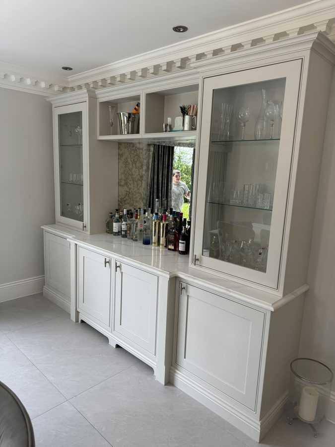A glazed drinks dresser with glass shelves and a mirrored back