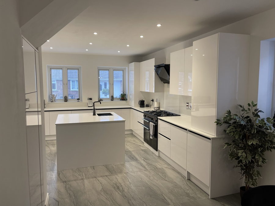 A handleless white gloss kitchen with an island and a range cooker