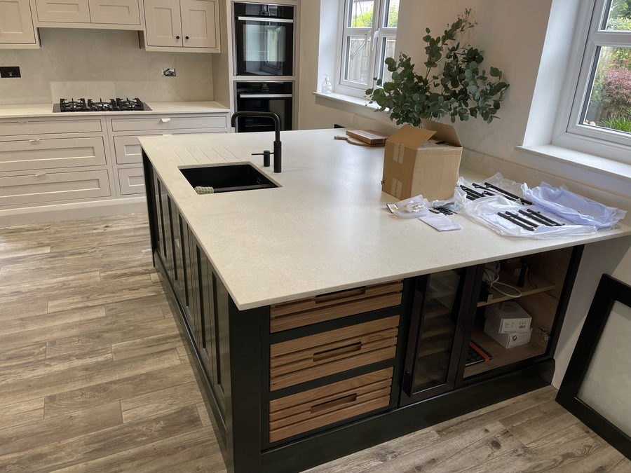 Cream shaker cabinetry with a deep green island and oak drawer interiors