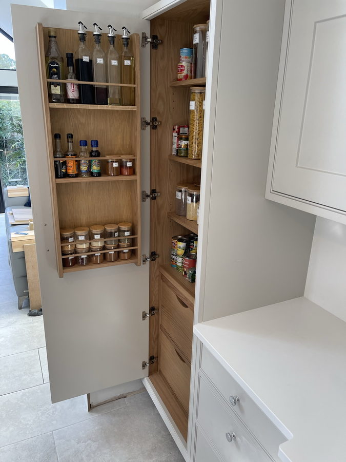 Larder doors fitted out with spice racks over an oak-lined interior