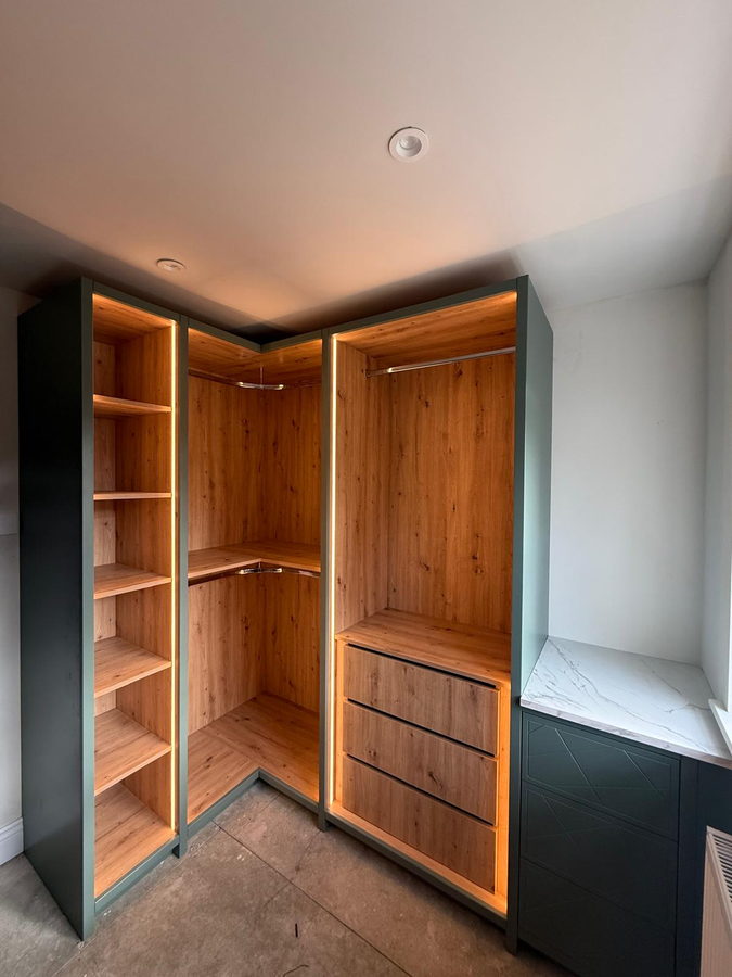 A walk-in corner with oak-effect interiors, hanging rails and drawers