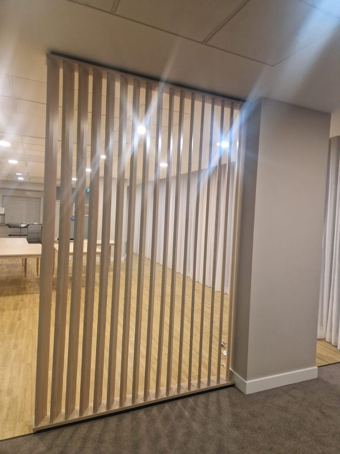 An ash slatted screen dividing a retirement-living lounge