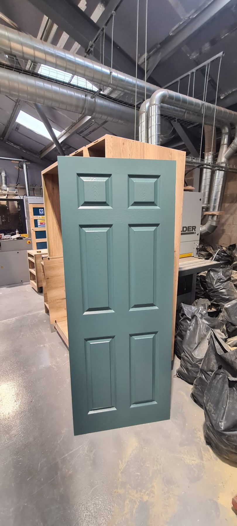 A sage green door standing in the workshop before delivery