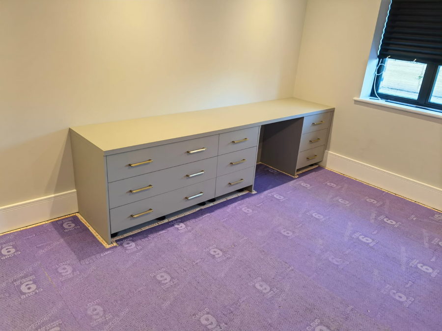 A fitted desk and drawer bank with brass handles, installed