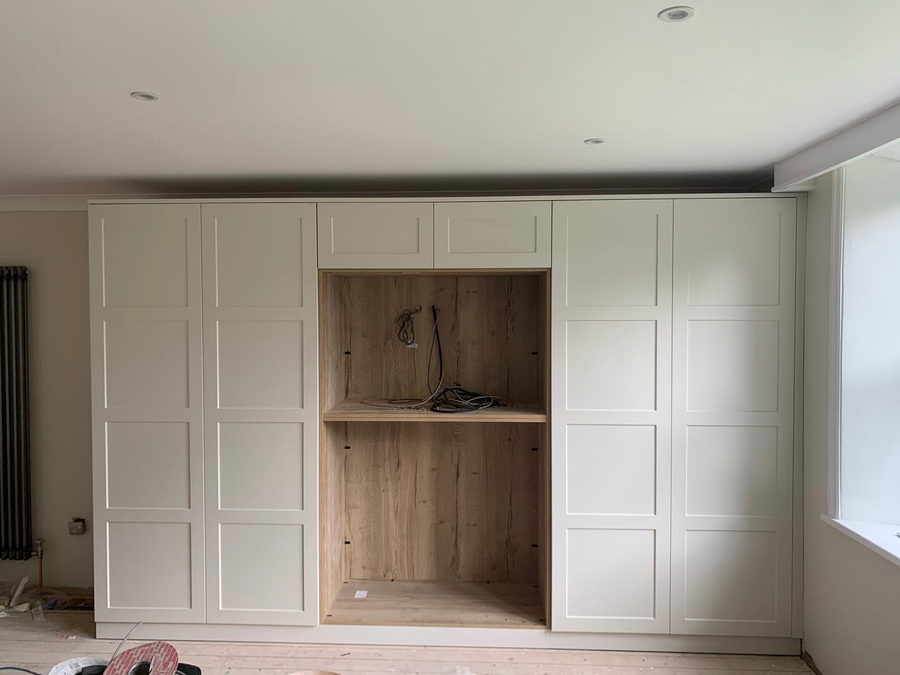 Cream panelled wardrobes either side of an oak-lined open recess