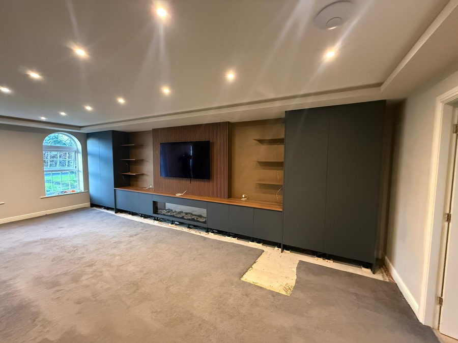 Charcoal cabinetry and oak shelving beside an arched window