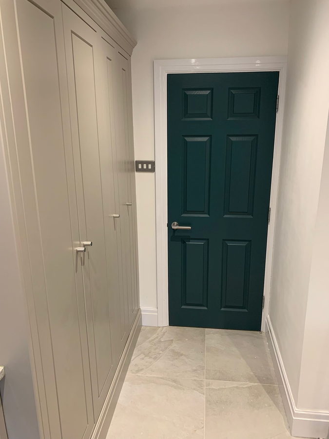 Full-height hallway cupboards leading to a painted door