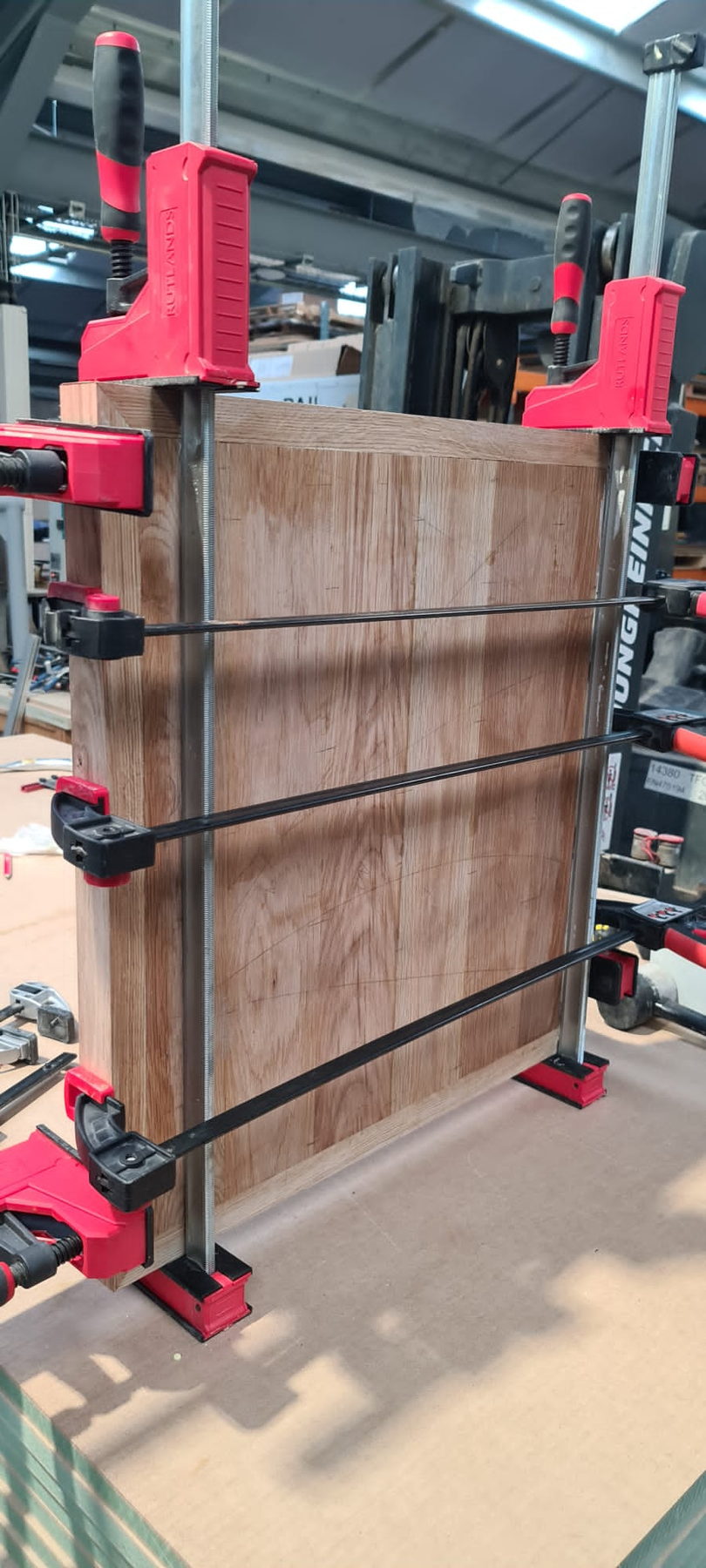 A solid timber panel clamped upright while the glue goes off
