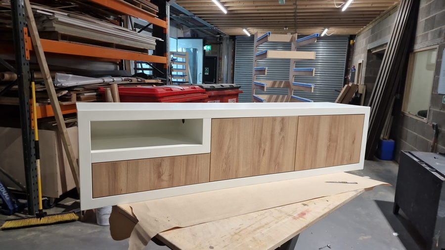 A long floating media unit being built on the workshop floor