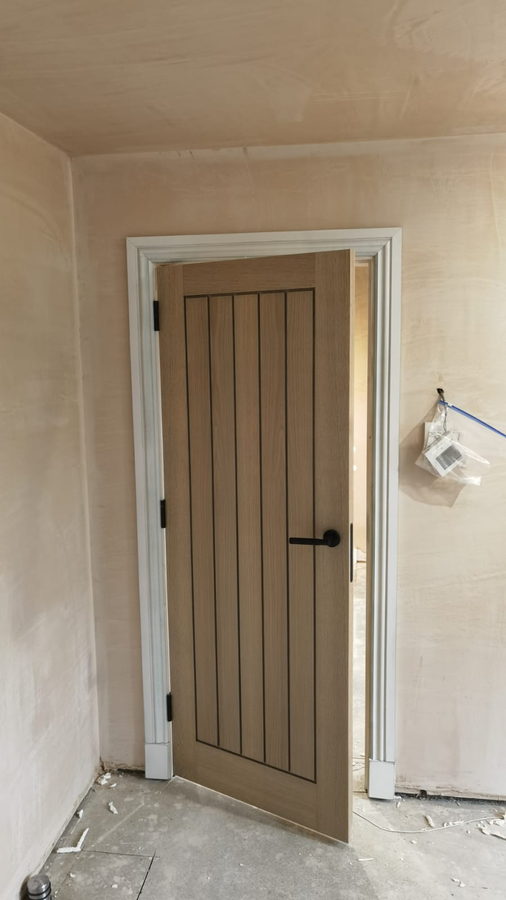 A vertical-boarded oak cottage door in a painted frame