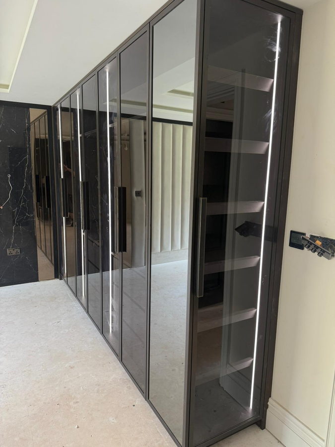 Dark-framed bronze glass doors to a run of display wardrobes