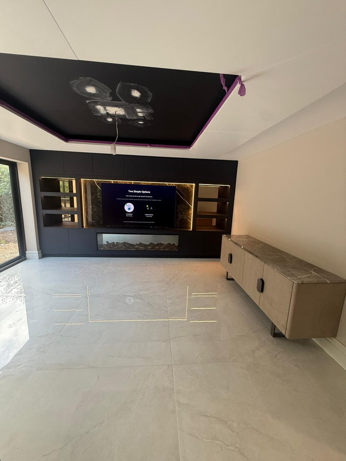Dark cabinetry and lit shelves across an open-plan room