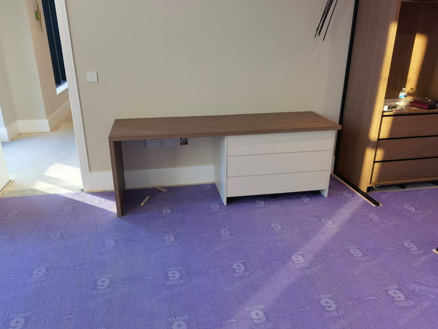 A desk with an oak top and drawer unit, beside fitted storage