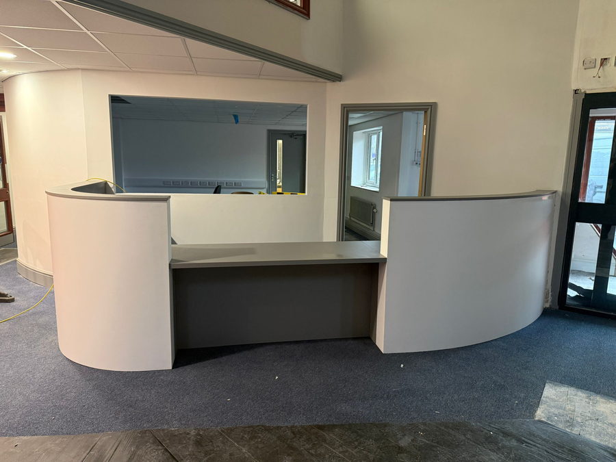 A curved reception desk with a dark counter, in an office fit-out