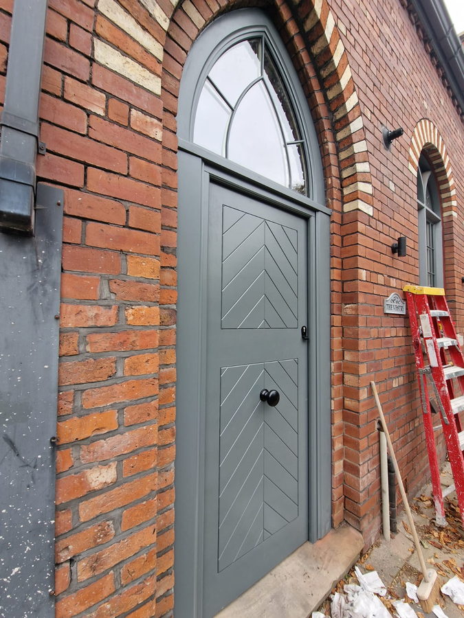 An arched gate with herringbone boarding, hung in a brick arch