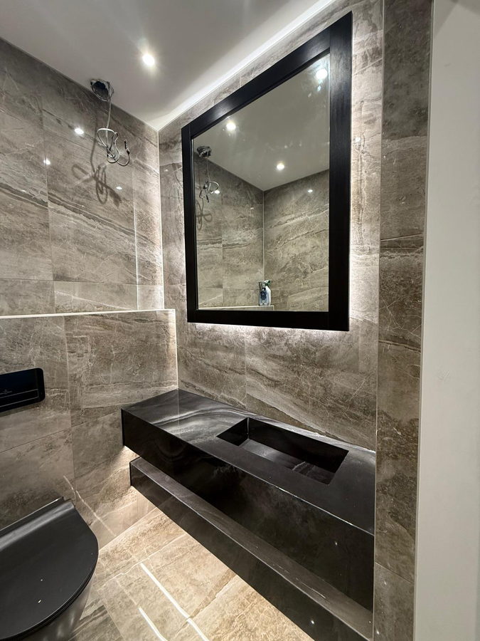 A slab-fronted vanity in a marble-effect shower room