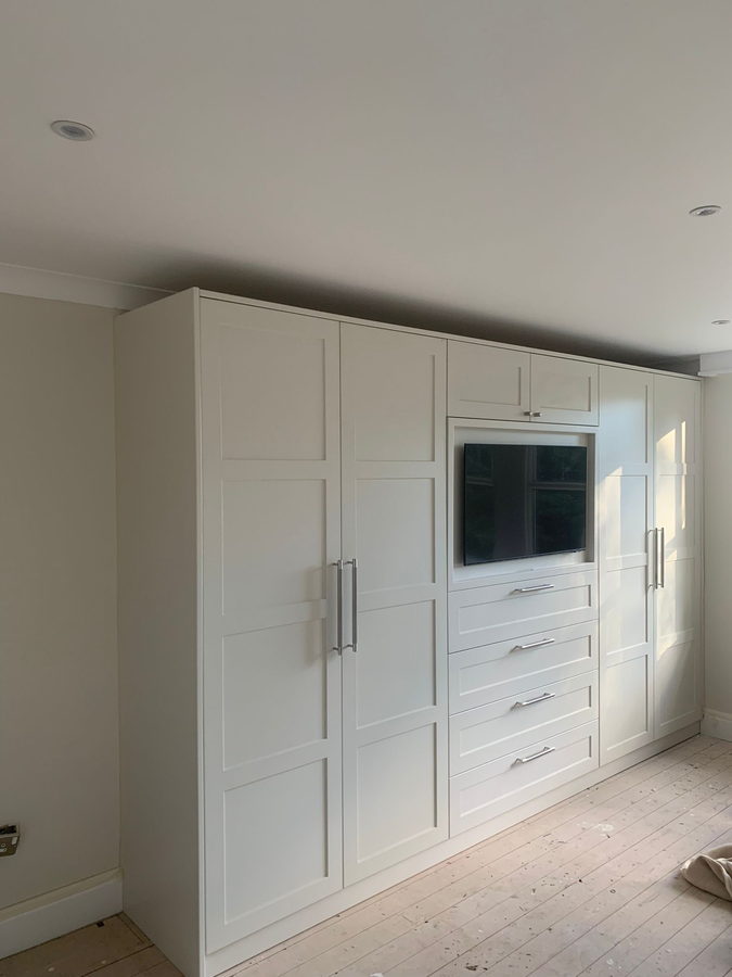 White shaker wardrobes with a recessed television and drawer bank
