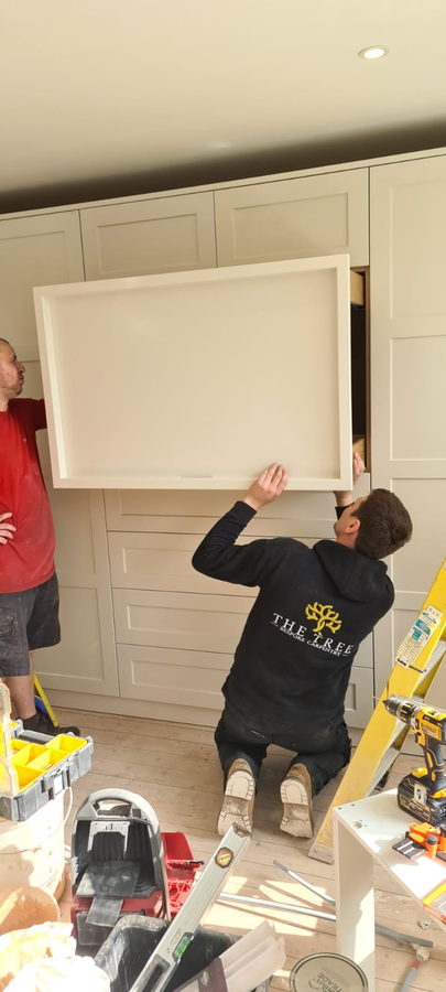 Two of the team setting a cabinet in place