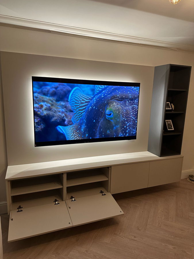 A backlit television recess with a full-height tower alongside