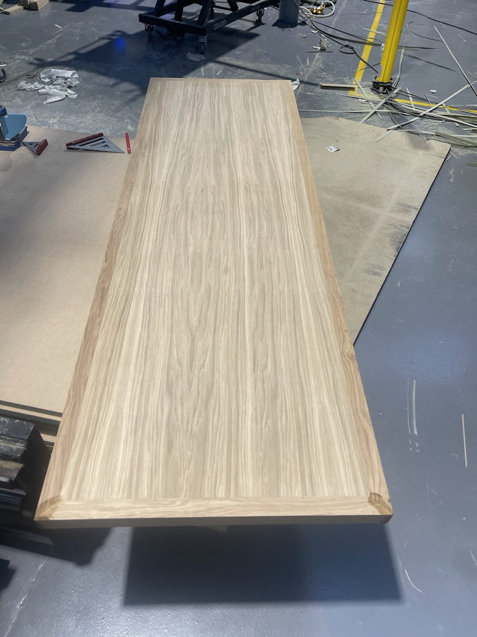 A long oak-veneered panel resting on the bench