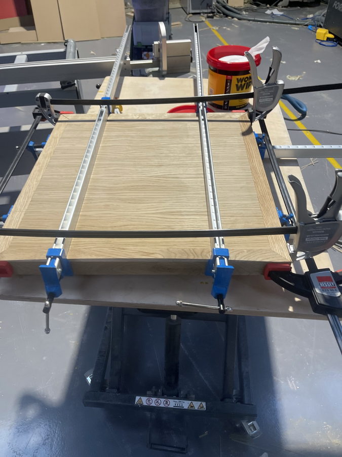 An oak panel clamped down while the edging is glued on